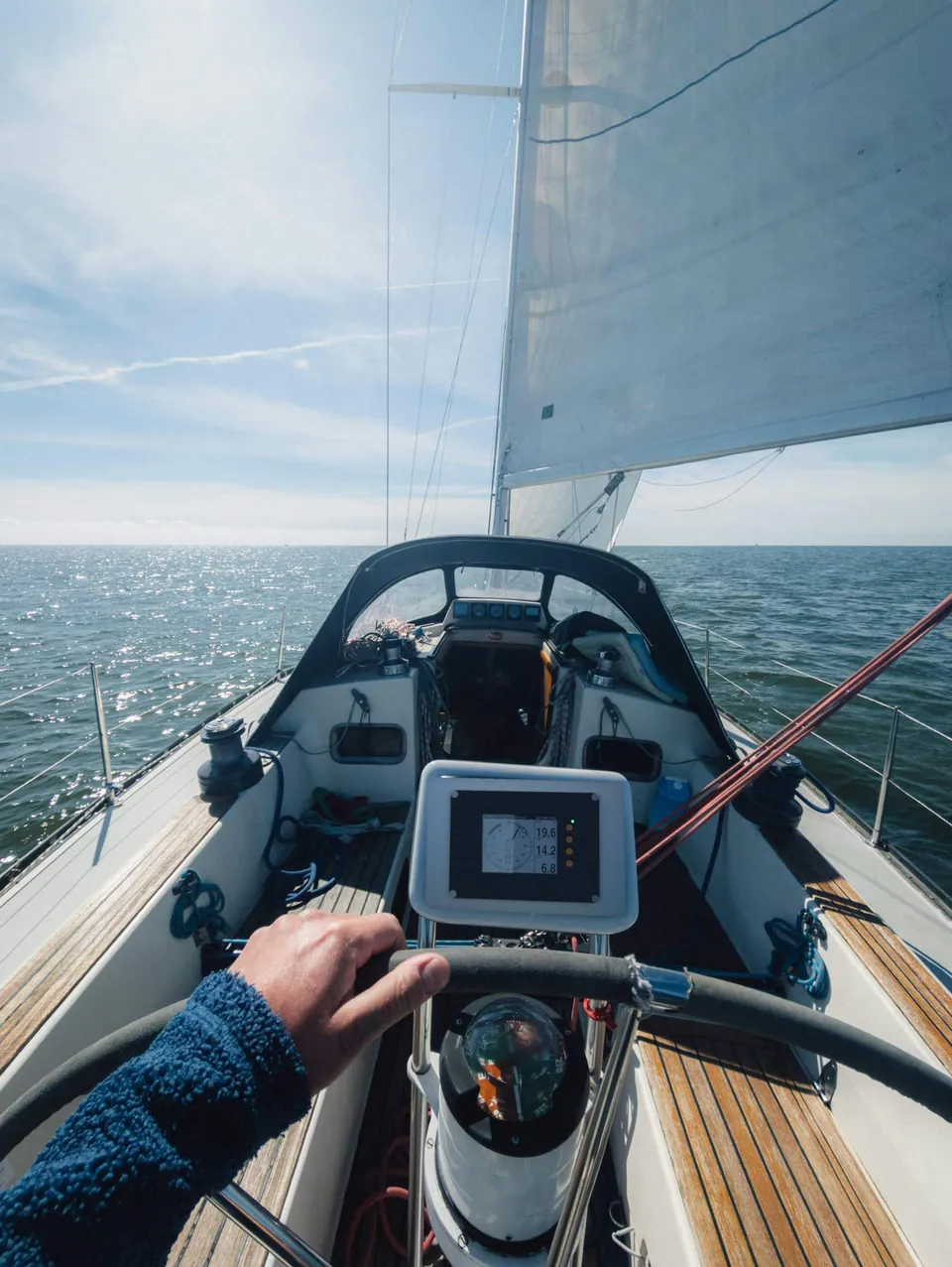 Photo composite: helmsman's view over the wheel with a SailNav display on the pedestal, North Sea ahead