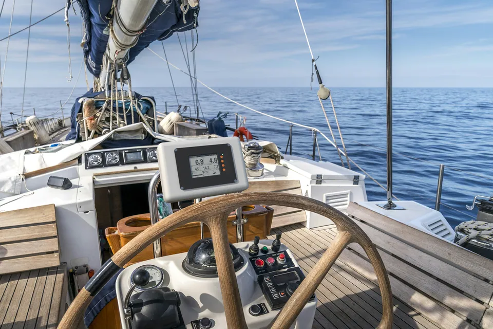 Photo composite: a SailNav display in a pod above the wheel of a cruising yacht, open sea ahead